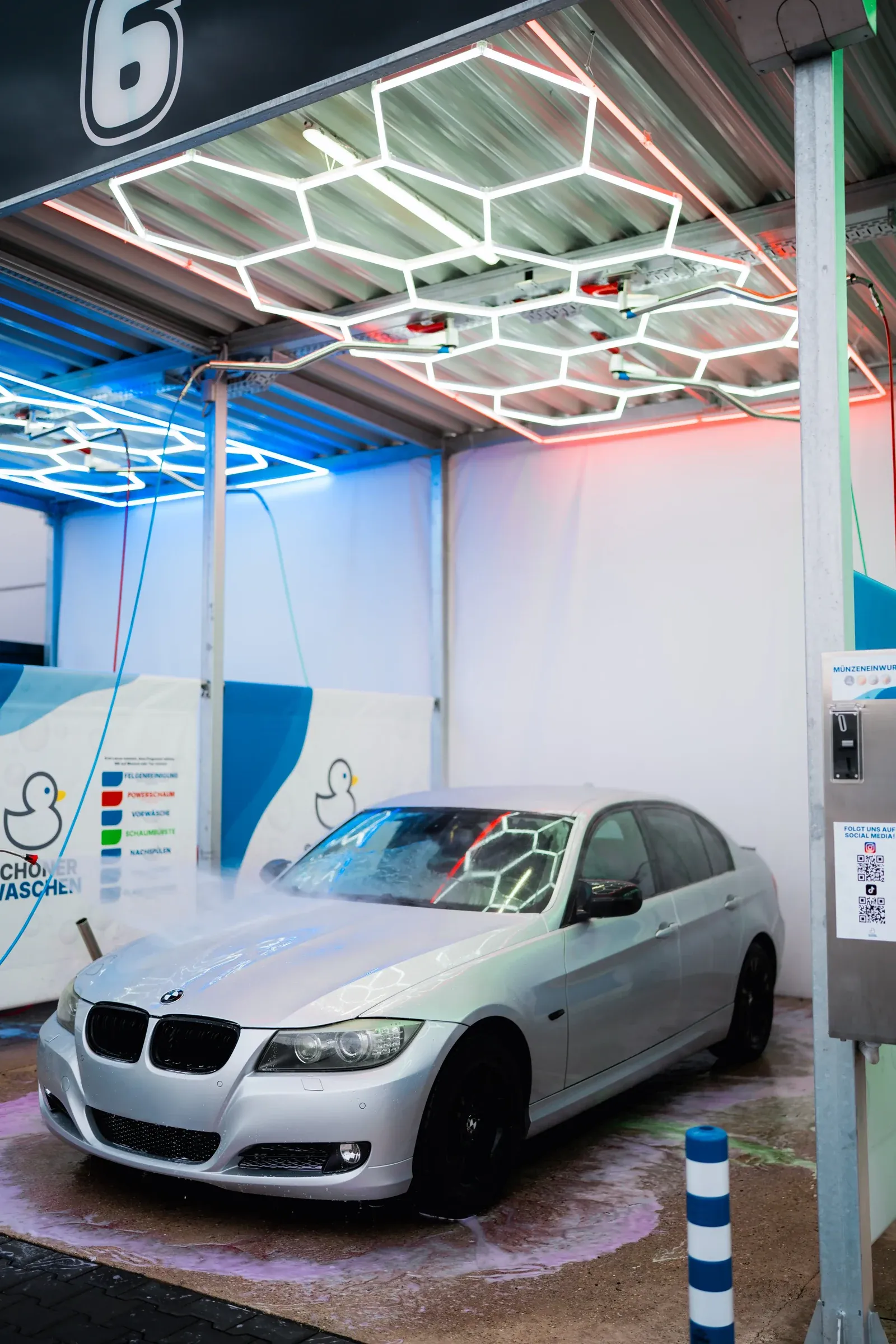 Ein Auto in einer Waschbox unter farbig leuchtender Hexagon-Beleuchtung