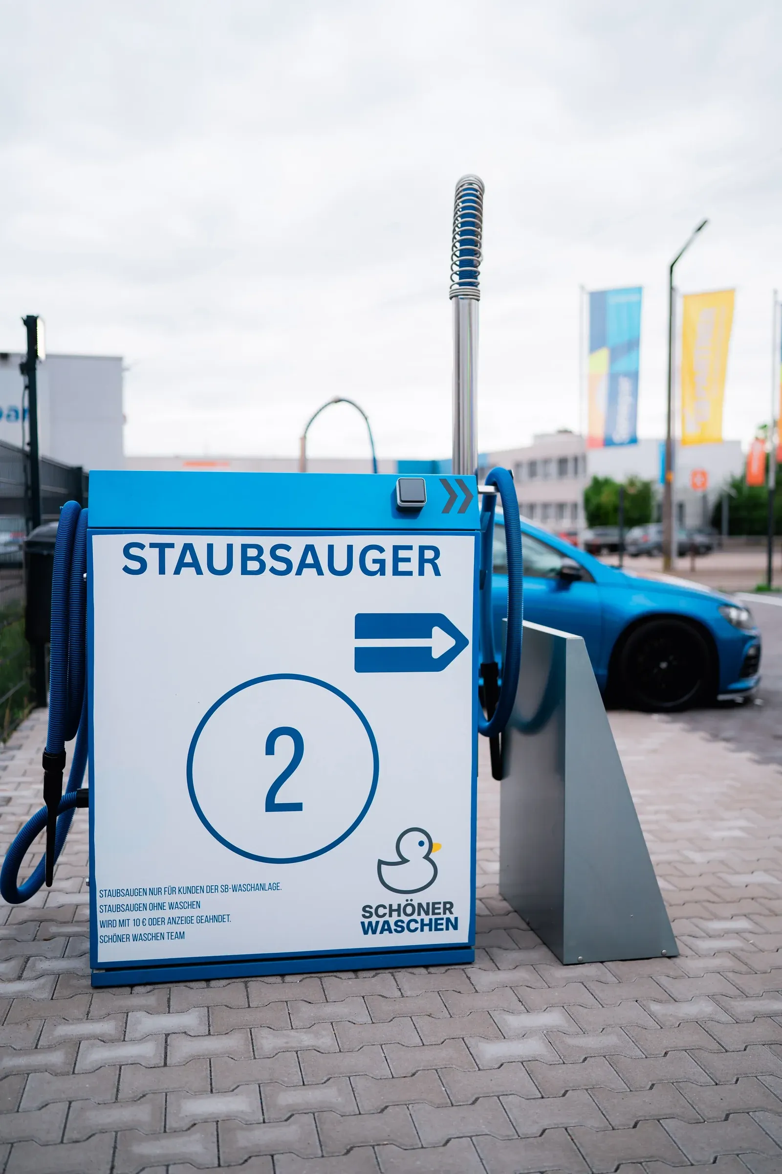 Blaues Hinweisschild „Staubsauger“ mit Pfeil und Stationsnummer 2